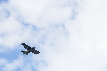 Old military aircraft in a blue sky with a cloud.