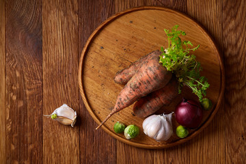 Colorful various of organic farm vegetables with fresh carrots on wooden rustic background, top view, selective focus