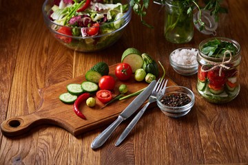 Fresh vegetable salad and ripe veggies on cutting board over wooden background, close up, selective focus