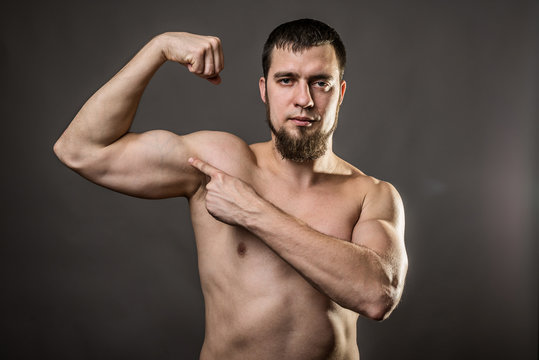 Handsome muscular bodybuilder on a gray background.