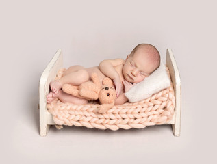 Newborn baby boy sleeping on a small bed