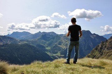 Fototapeta na wymiar Trekker enjoying the view on the valley (Upper Seriana Valley). Orobie Alps, Lombardy, Italy