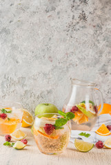 Summer cold cocktail, fruit and berry white sangria with apple, lemon, oranges and raspberry. light concrete background, copy space