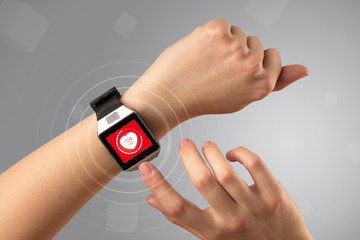 Naked female hand with smartwatch and with heart rate icon on the watch