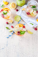 Summer cold cocktail, fruit and berry white sangria with apple, lemon, oranges and raspberry. light concrete background, copy space top view