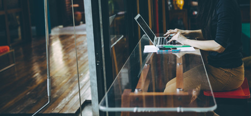 Beautiful young Asian girl working at a coffee shop with a laptop.