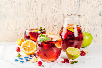Summer cold cocktail, fruit and berry red wine sangria with apple, lemon, oranges and raspberry. light background, copy space