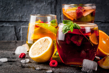 Summer cold cocktail, set of three fruit and berry sangria drink. red white pink, with apple, lemon, oranges and raspberry. dark background, copy space