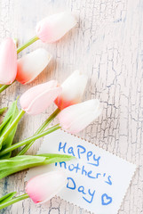 Mother's Day concept, greeting card background. Flowers tulips and greeting note Happy Mother's Day on a light concrete table, copy space top view