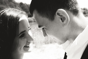 Wedding couple are looking at each other outdoors near the blue lake with reeds. Bride in puffy...