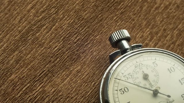 Vintage White Stopwatch on the Brown Structural Background Rotates the Arrow. Time lapse. Stopwatch Clock Face. Close Up. Dial Hands, Minutes Hours Seconds. Macro Shot. The second hand on the dial