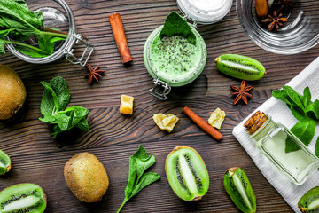 Skin care cosmetic with kiwi scrub on desk background top view