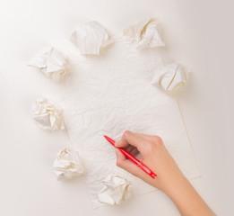 Female hand trying to write next to a few crumpled paper balls 