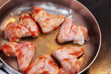 Chicken wings in sauce are fried in a pan. Cooking. Meat close-up