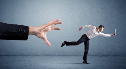 Young miniature businessman running from a big hand with blue background