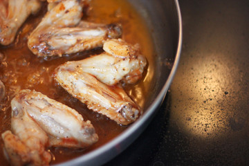 Chicken wings in sauce are fried in a pan. Cooking. Meat close-up