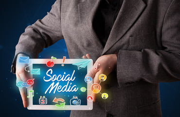 Fototapeta na wymiar Casual businessman holding tablet with social media icons