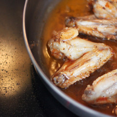 Chicken wings in sauce are fried in a pan. Cooking. Meat close-up