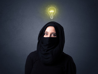 Young muslim woman wearing niqab with lit lightbulb above her head