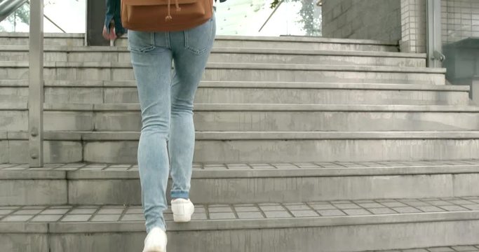 Woman walking up stair and using mobile phone
