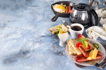 English breakfast. Fried eggs, sausages, toasts, tomatoes on stone table.