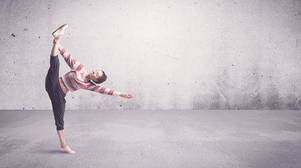 A beautiful young hip hop dancer dancing contemporary urban street dance in empty clear grey wall...