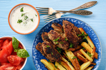 Cevapcici, balkanian grilled meat sausages with fries and yogurt dip.