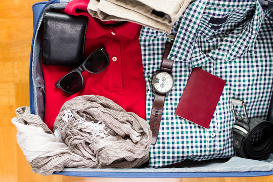 Open traveler's bag with passport, clothing and accessories. Travel and vacations concept.