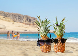Couple of attractive pineapples in love on the sand against atlantic ocean. Tropical summer vacation concept. Sunny day on the Diego Hernandez beach on Tenerife. Honeymoon