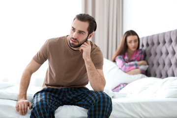 Young couple ignoring each other after having argument in bedroom