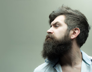 Obraz premium Barbershop or hairdresser concept. Macho on strict face, wears unbuttoned shirt. Man with beard, mustache and stylish hair, light background. Guy with modern hairstyle visited hairdresser, side view.