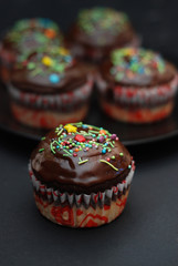 Homebaked Chocolate Muffins for Easter with colored Conffeti. Dark Background. Sweet Dessert for Breakfast.