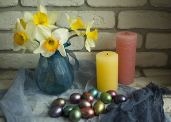 bright daffodils and Easter eggs with candles on a shelf