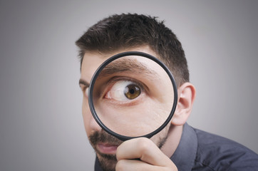 Fototapeta na wymiar Portrait of a curious man looking through magnifying glass