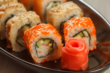 Close up pickled ginger in the form of red rose and sushi rolls - Uramaki California, Uramaki with Conger on the background. Japanese cuisine