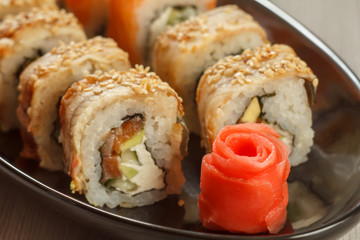 Close up pickled ginger in the form of red rose and sushi rolls - Uramaki with Conger on the background. Japanese cuisine