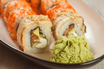 Close up wasabi and sushi rolls - Uramaki with Conger, Uramaki California on the background. Japanese cuisine