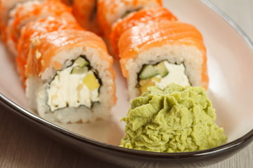 Close up wasabi and sushi rolls - Uramaki Philadelphia on the background. Japanese cuisine