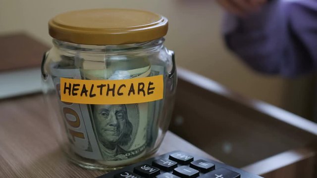 Caucasian male putting a glass jar put in a drawer  table with his savings for future healthcare