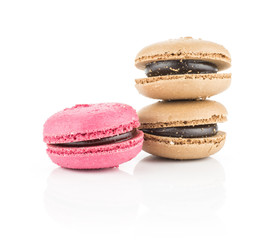 Three French macarons (two chocolate and one pink with raspberry) isolated on white background.
