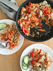 rice with vegetables and chicken in a frying pan and on plates for dinner.