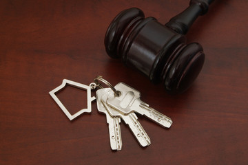 Judge gavel and keys with key holder on wooden table