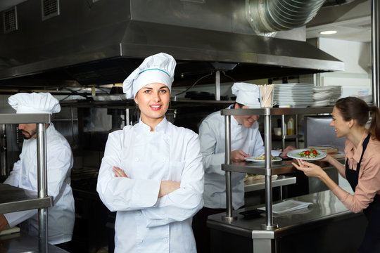 Portrait of young confident woman chef in kitchen of restaurant