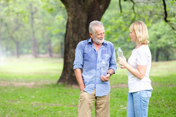 Portrait senior couple standing drinking water at the park