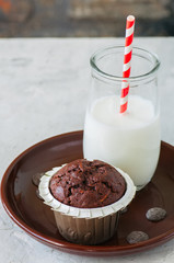 One chocolate zucchini muffin and glass of milk on a white stone background. Copy space.