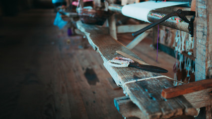 Vintage scissors hang on the nail. The background is the side of the old workshop. Shallow depth of field, focus on scissors