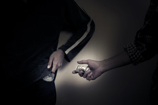 Male hand sending roll of money to buy drugs