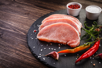 Raw pork chops on cutting board and vegetables