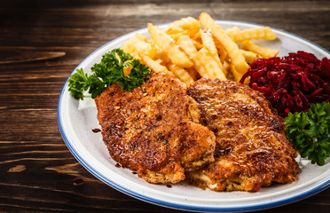 Grilled steak, French fries and vegetables on wooden background