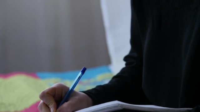 sed young woman lies on a bed and writes in her diary. adolescent experiences. 4K